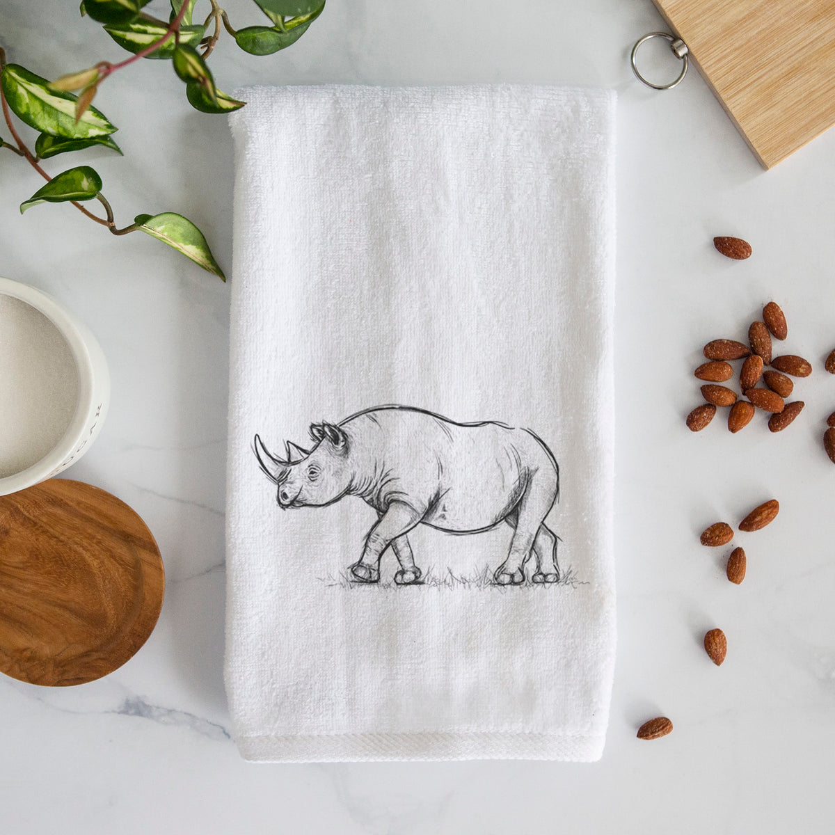 White hand towel printed with a black ink illustration of a black rhinoceros walking.