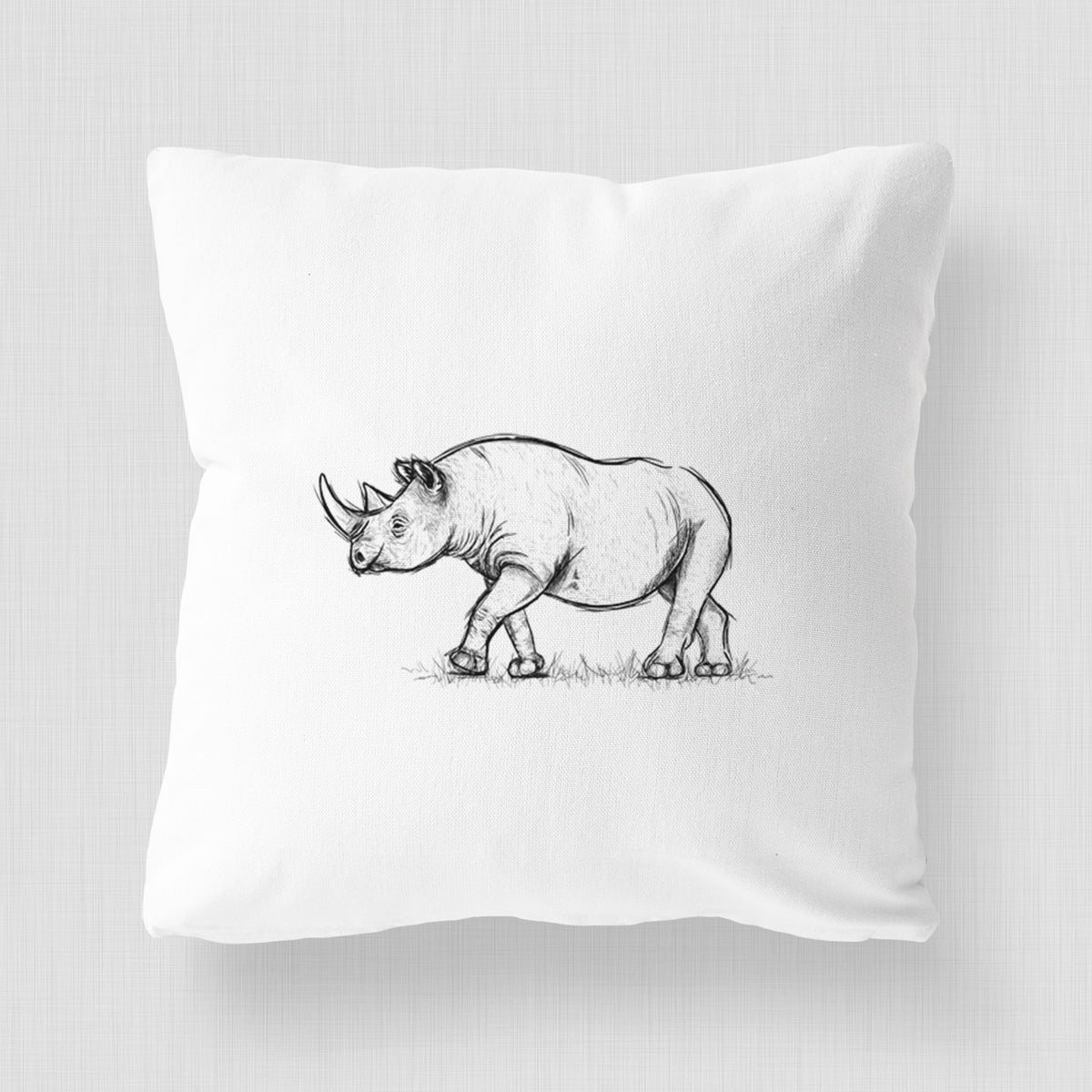 White pillow cover printed with a black ink illustration of a black rhinoceros walking.