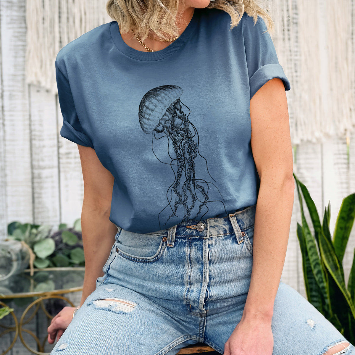 Woman wearing a steel blue lightweight cotton t-shirt printed with a black ink illustration of a black sea nettle jellyfish with long trailing tentacles.