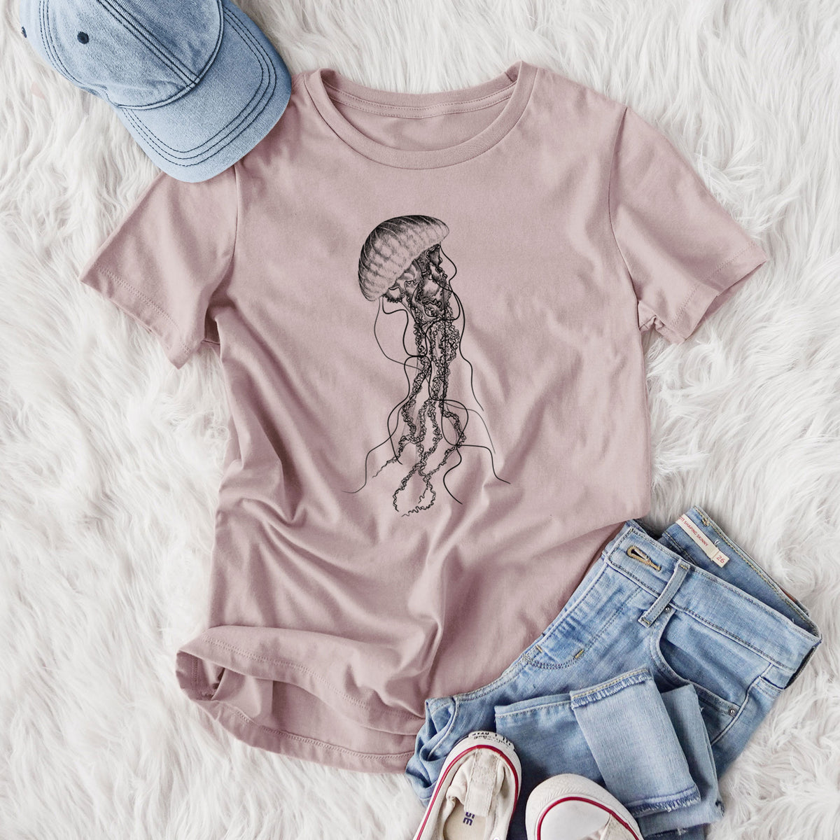 Women's relaxed fit cotton t-shirt printed with a black ink illustration of a black sea nettle jellyfish with long trailing tentacles, styled flat on a white faux fur rug with jeans.