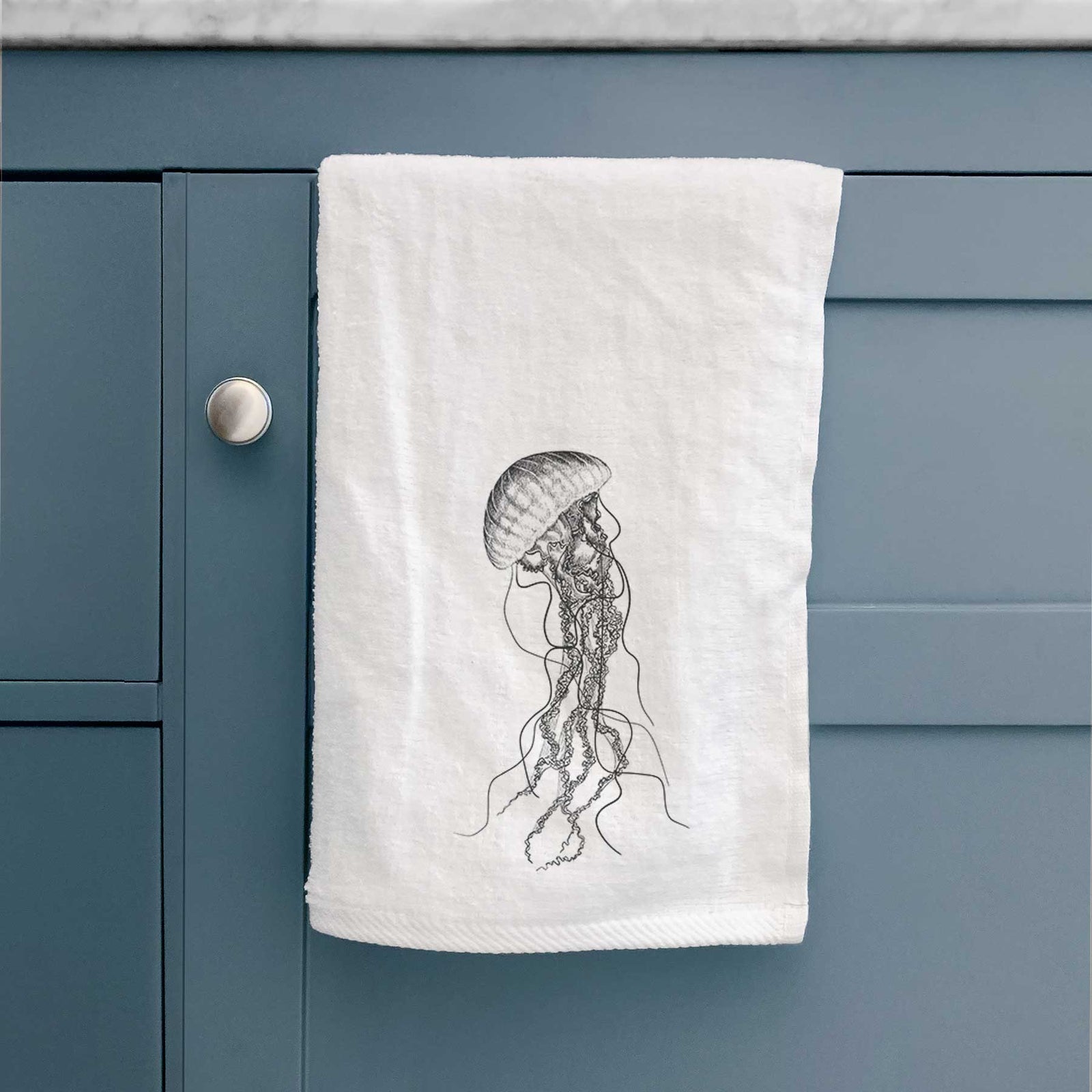 White hand towel printed with a black ink illustration of a black sea nettle jellyfish with long trailing tentacles.