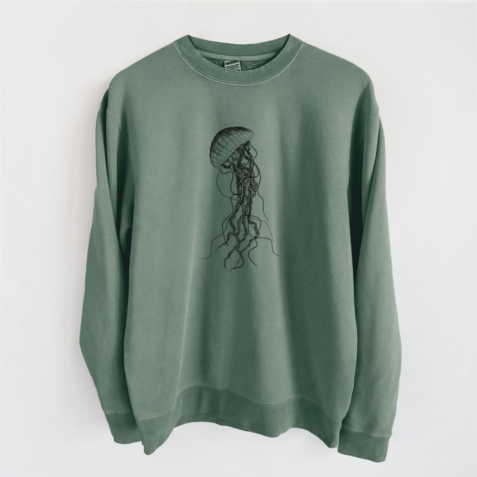 Alpine green pigment dyed crewneck sweatshirt laid flat, printed with a black ink illustration of a black sea nettle jellyfish with long trailing tentacles.