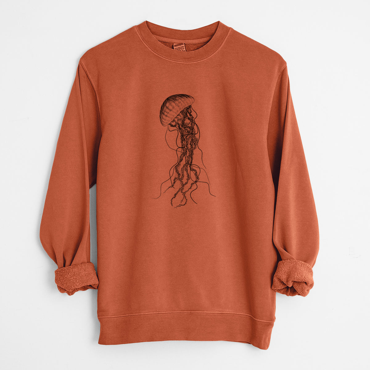 Amber orange pigment dyed crewneck sweatshirt laid flat with the sleeves rolled, printed with a black ink illustration of a black sea nettle jellyfish with long trailing tentacles.
