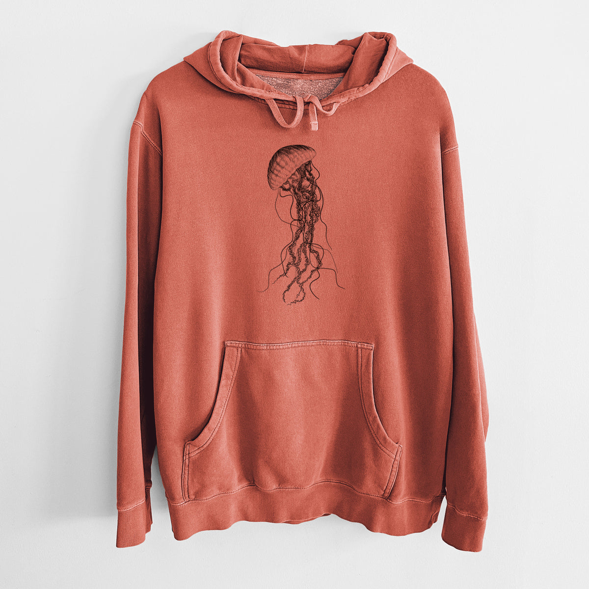 Amber orange pigment dyed hoodie laid flat, printed with a black ink illustration of a black sea nettle jellyfish with long trailing tentacles.