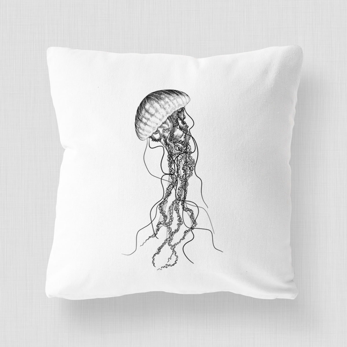 White pillow cover printed with a black ink illustration of a black sea nettle jellyfish with long trailing tentacles.