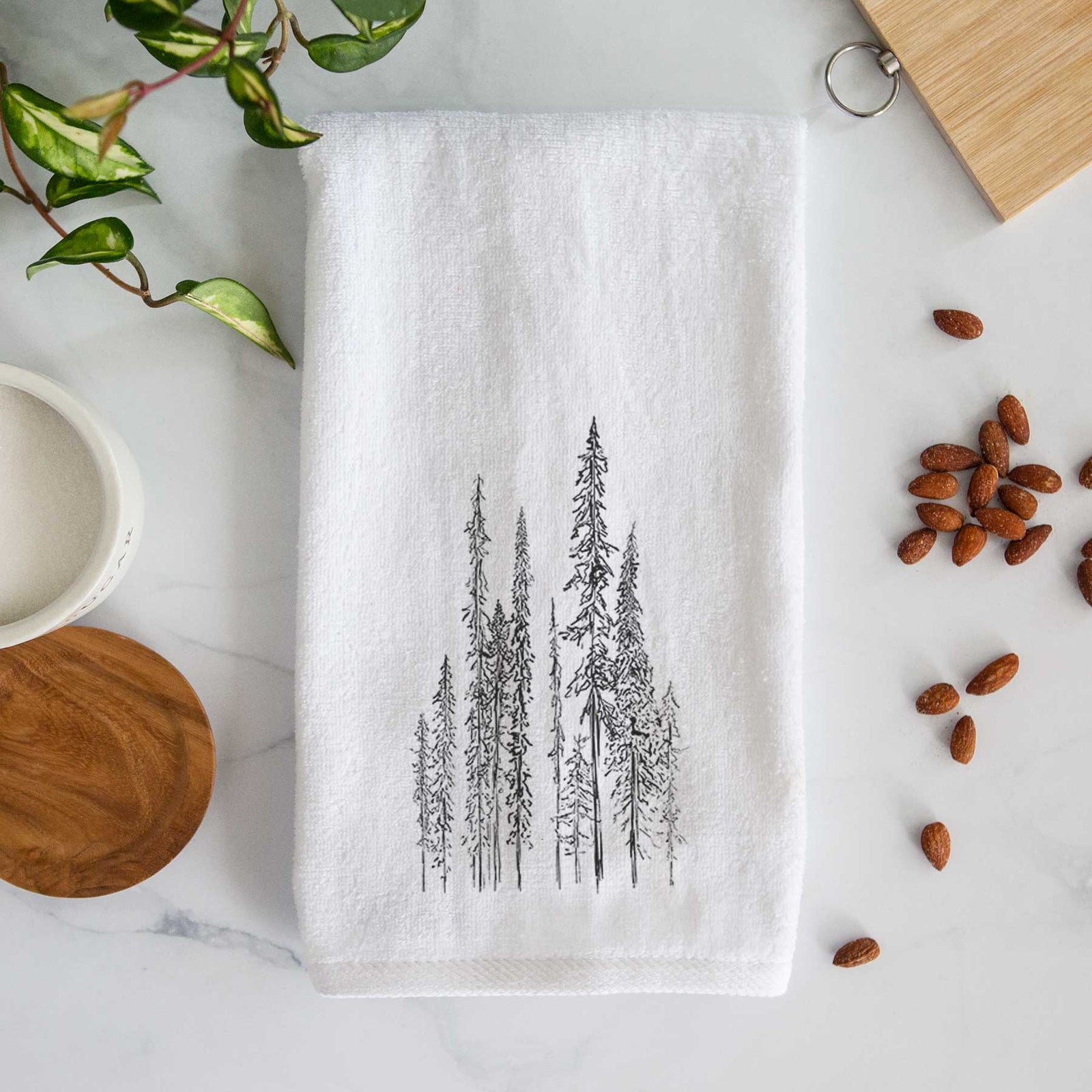 White hand towel printed with a black ink illustration of a stand of tall, narrow black spruce trees.