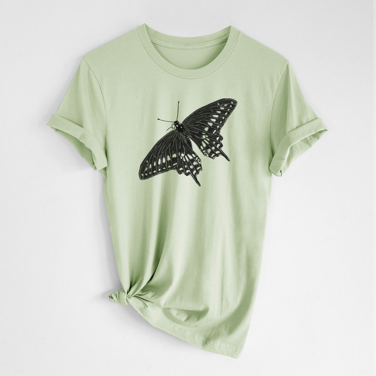 Spring green lightweight cotton t-shirt laid flat with the sleeves rolled, printed with a detailed black ink illustration of a black swallowtail butterfly with its wings spread.