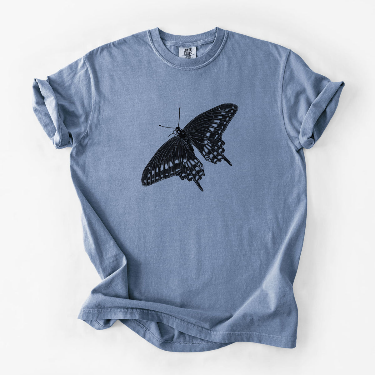 Blue jean Comfort Colors t-shirt laid flat, printed with a detailed black ink illustration of a black swallowtail butterfly with its wings spread.