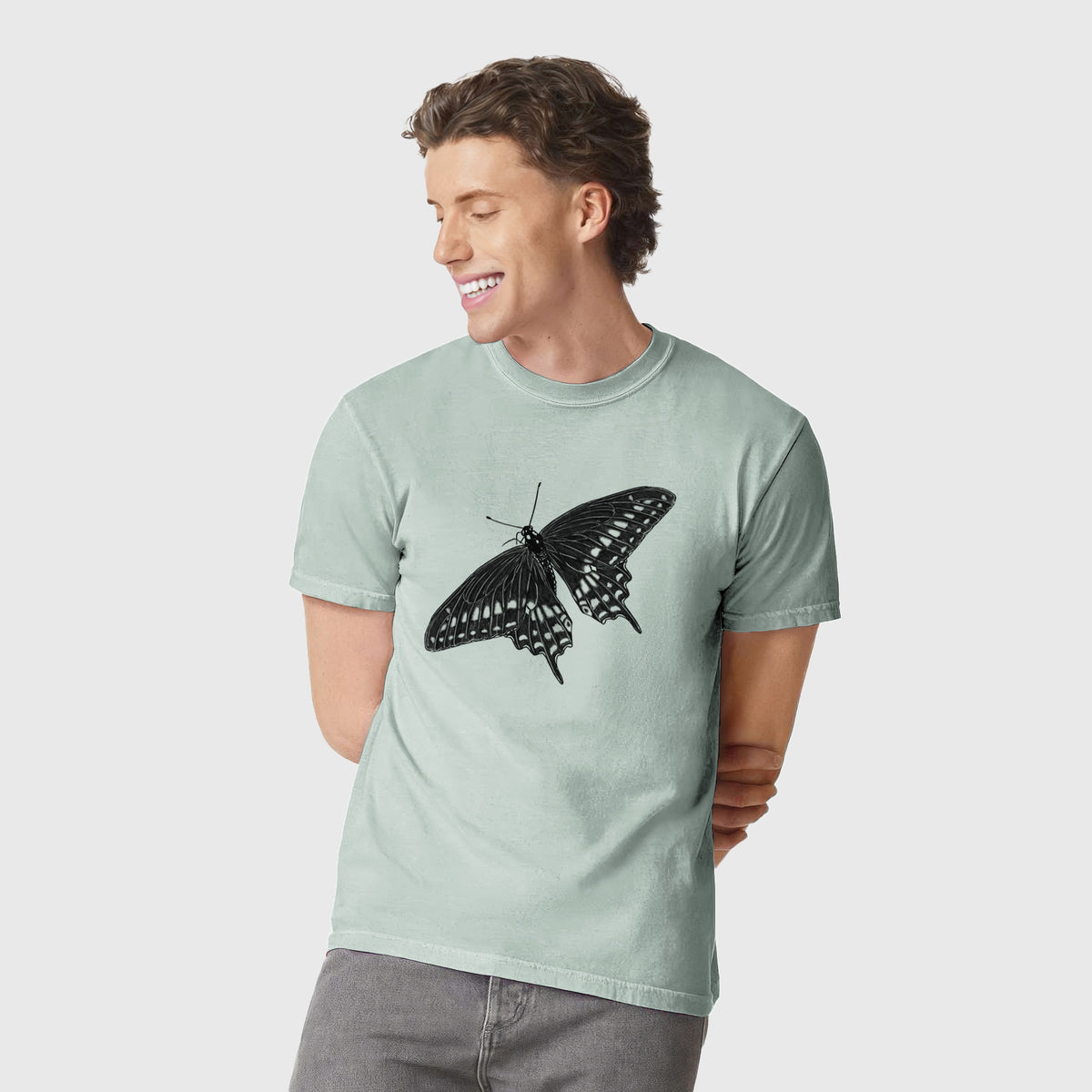 Man wearing a Comfort Colors t-shirt printed with a detailed black ink illustration of a black swallowtail butterfly with its wings spread.