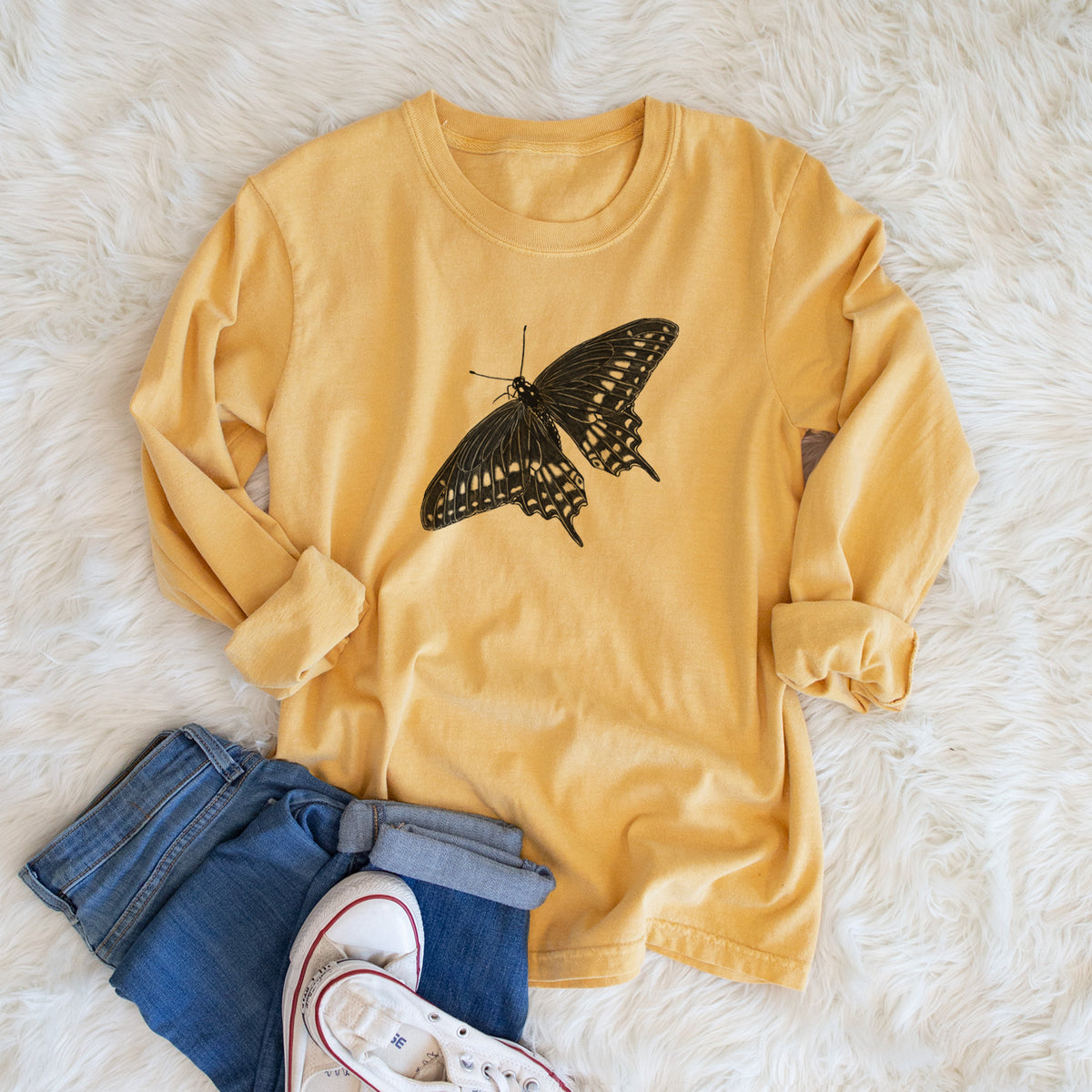 Golden wheat yellow Comfort Colors long sleeve shirt printed with a detailed black ink illustration of a black swallowtail butterfly with its wings spread, shown in a lifestyle photo.