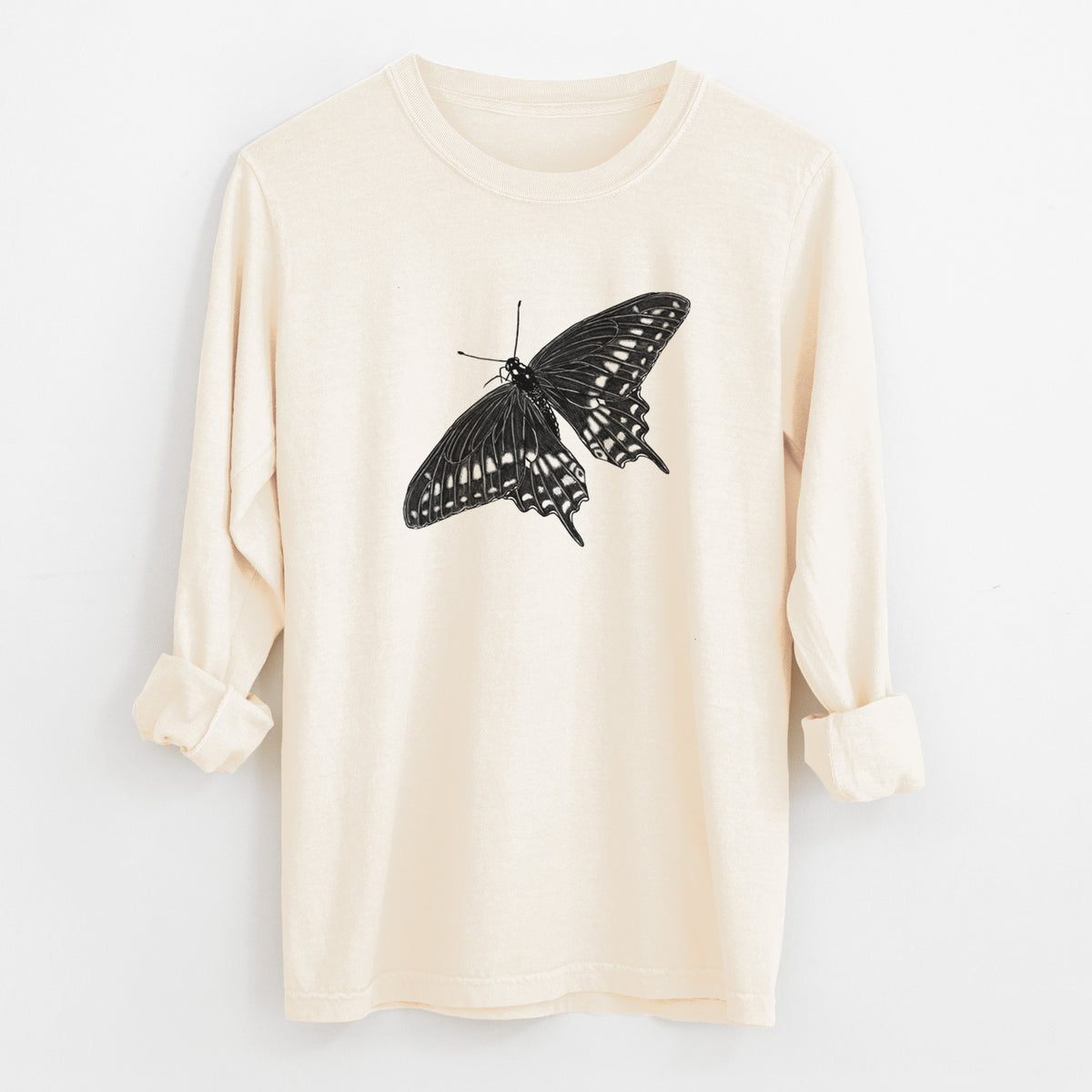 Ivory Comfort Colors long sleeve shirt laid flat with the cuffs rolled, printed with a detailed black ink illustration of a black swallowtail butterfly with its wings spread.