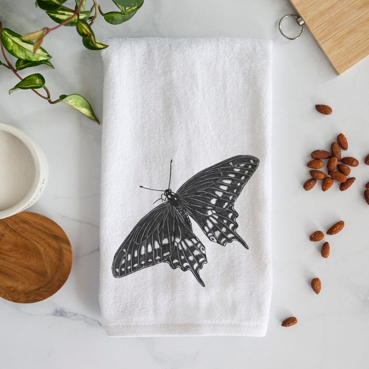 White hand towel printed with a detailed black ink illustration of a black swallowtail butterfly with its wings spread.