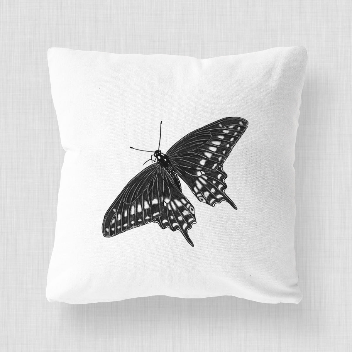 White pillow cover printed with a detailed black ink illustration of a black swallowtail butterfly with its wings spread.