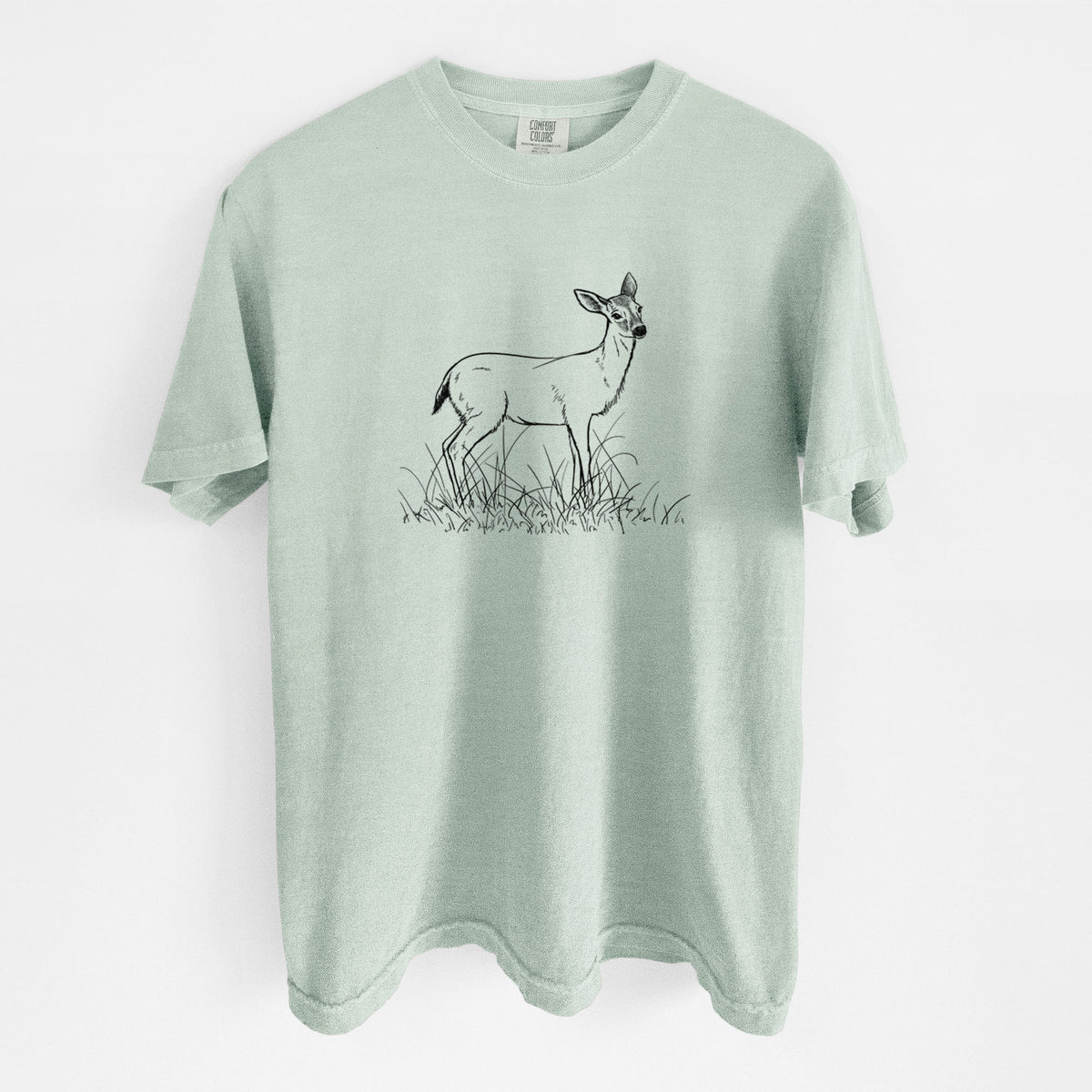 Bay green Comfort Colors t-shirt laid flat, printed with a black ink sketch of a black-tailed deer standing in tall grass.