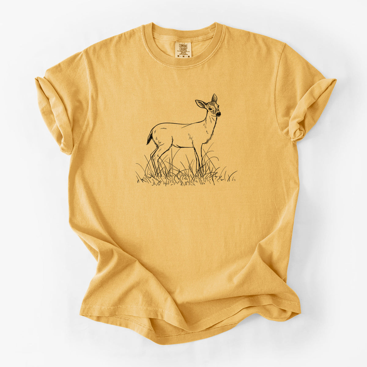 Golden wheat yellow Comfort Colors t-shirt laid flat, printed with a black ink sketch of a black-tailed deer standing in tall grass.