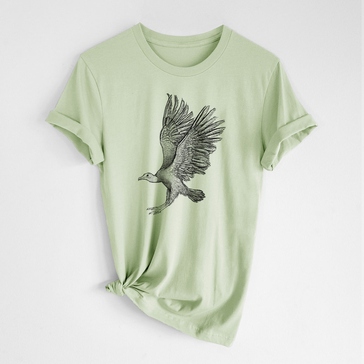 Spring green lightweight cotton t-shirt laid flat with the sleeves rolled, printed with a detailed black ink illustration of a black vulture landing with its wings spread.
