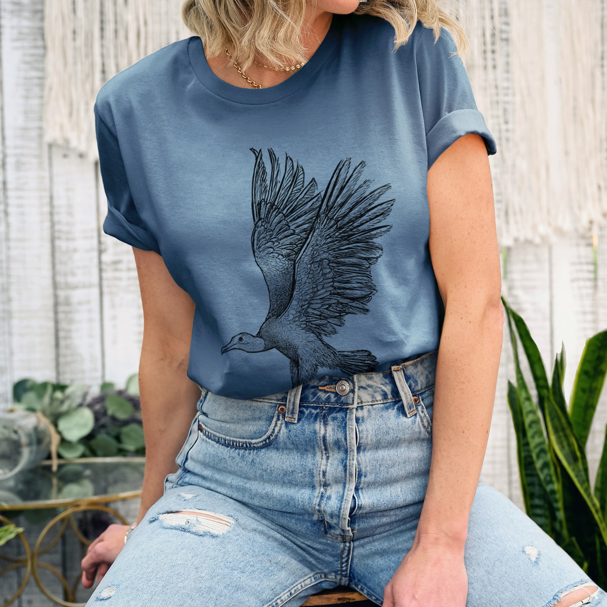 Woman wearing a steel blue lightweight cotton t-shirt printed with a detailed black ink illustration of a black vulture landing with its wings spread.
