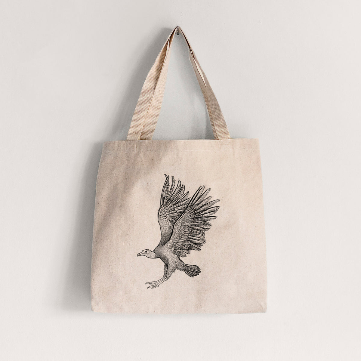 Natural canvas tote bag printed with a detailed black ink illustration of a black vulture landing with its wings spread.