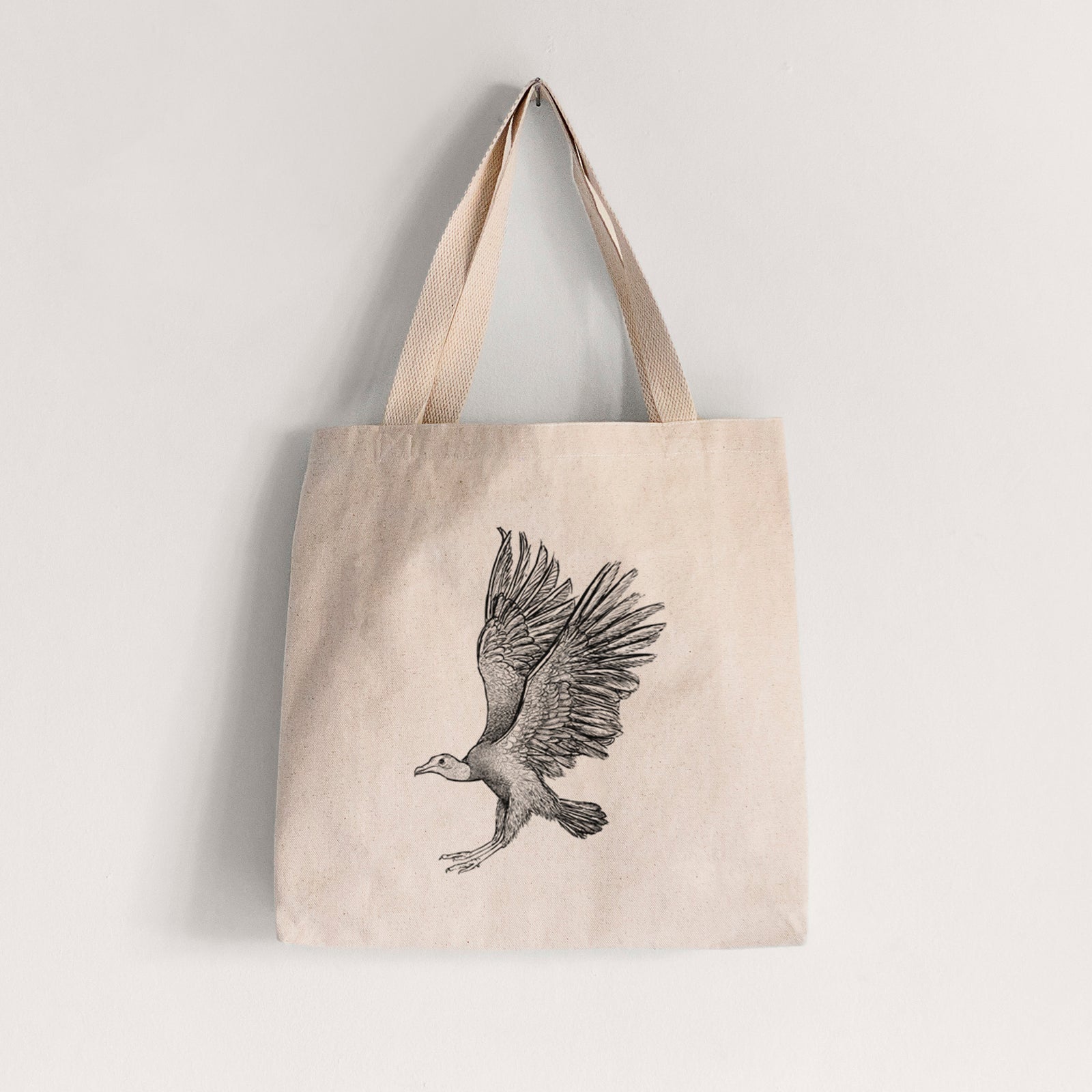 Natural canvas tote bag printed with a detailed black ink illustration of a black vulture landing with its wings spread.