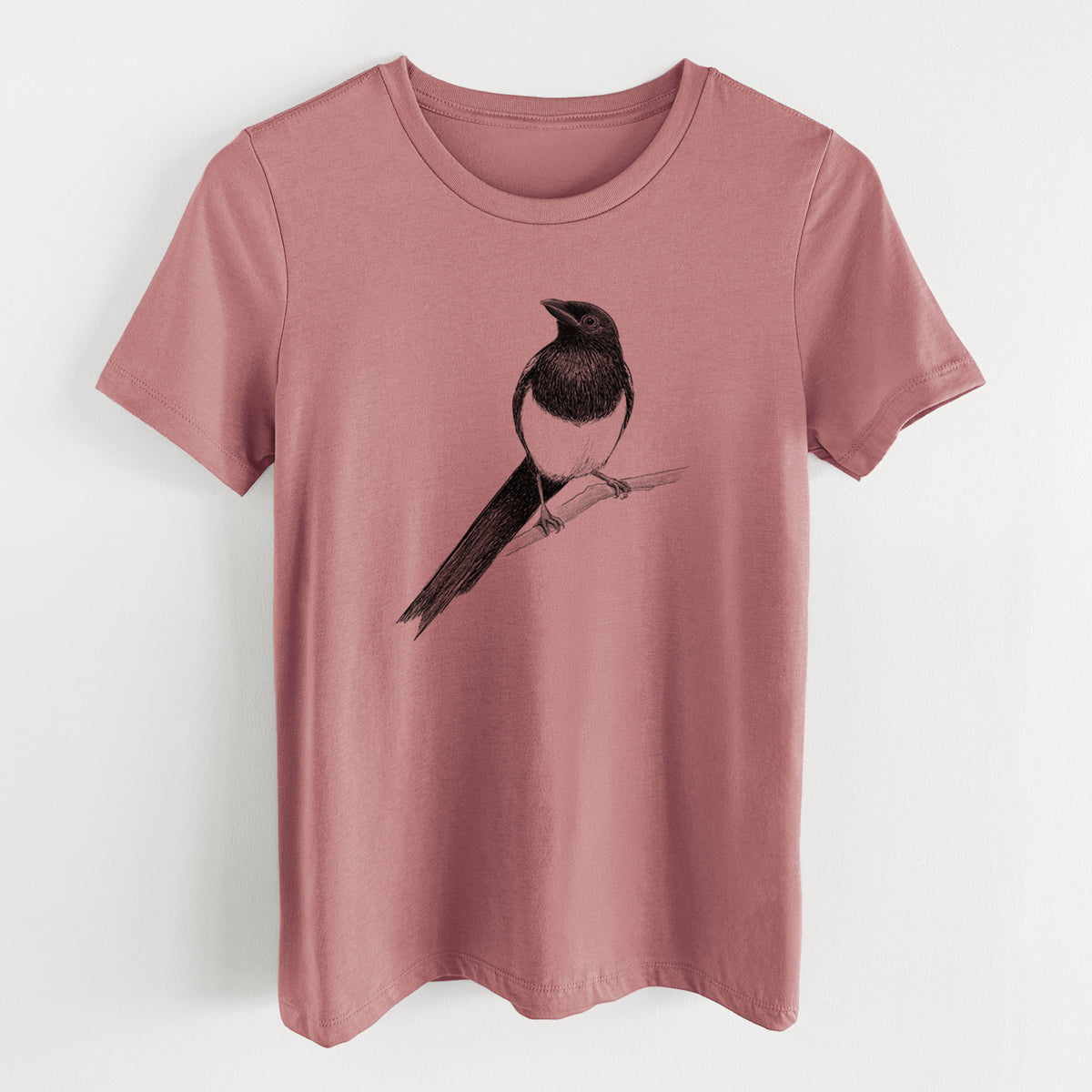 Mauve pink women's relaxed fit cotton t-shirt laid flat, printed with a detailed black ink sketch of a black-billed magpie perched on a branch with its long tail.