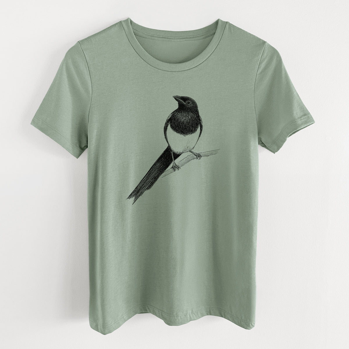 Sage green women's relaxed fit cotton t-shirt laid flat, printed with a detailed black ink sketch of a black-billed magpie perched on a branch with its long tail.