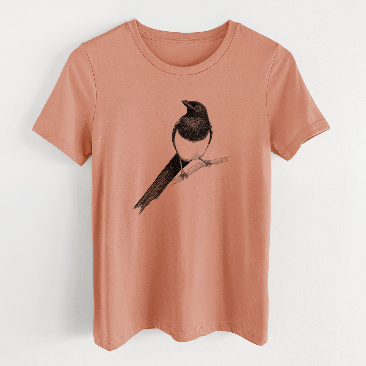 Terracotta orange women's relaxed fit cotton t-shirt laid flat, printed with a detailed black ink sketch of a black-billed magpie perched on a branch with its long tail.