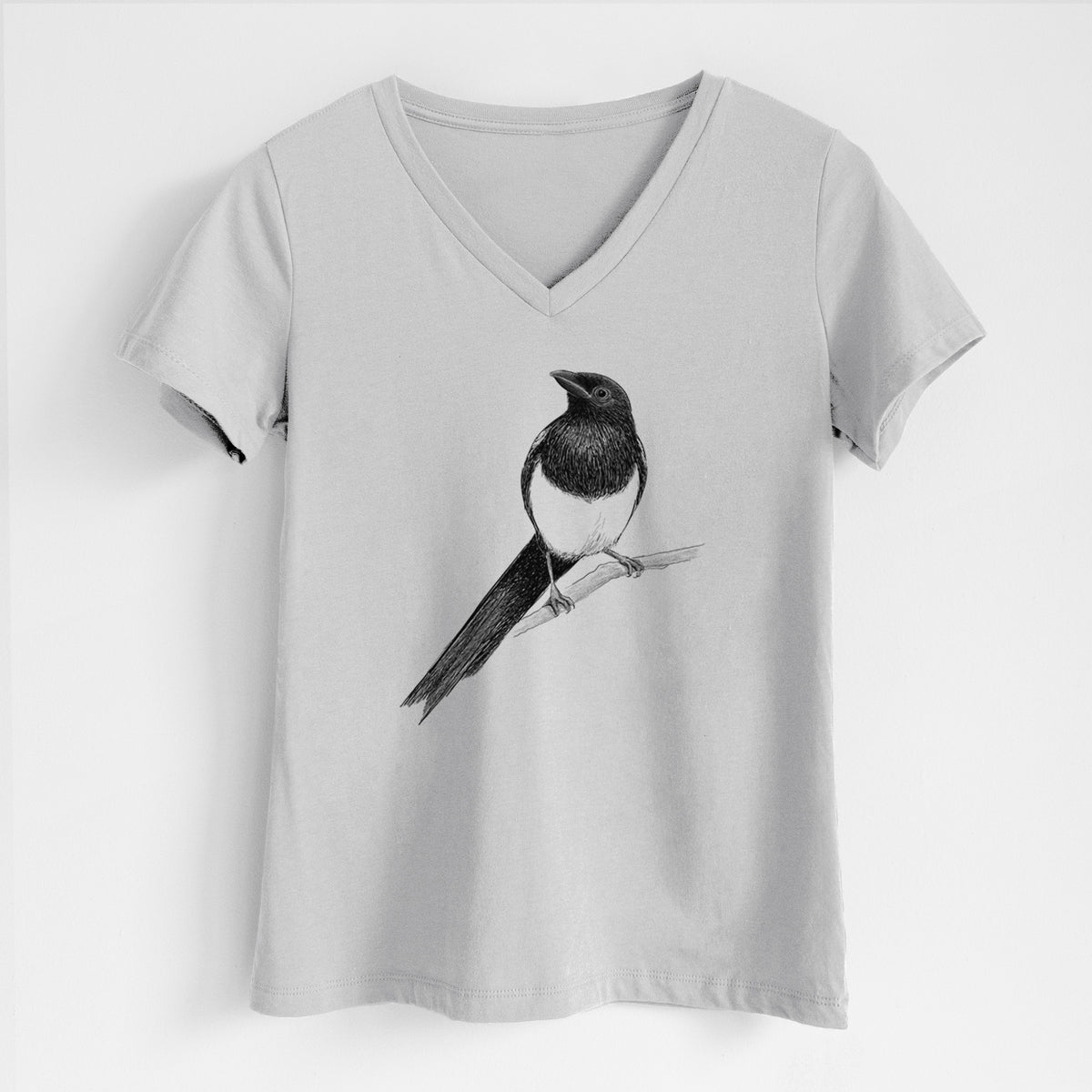 Lunar grey women's relaxed fit cotton V-neck t-shirt laid flat, printed with a detailed black ink sketch of a black-billed magpie perched on a branch with its long tail.