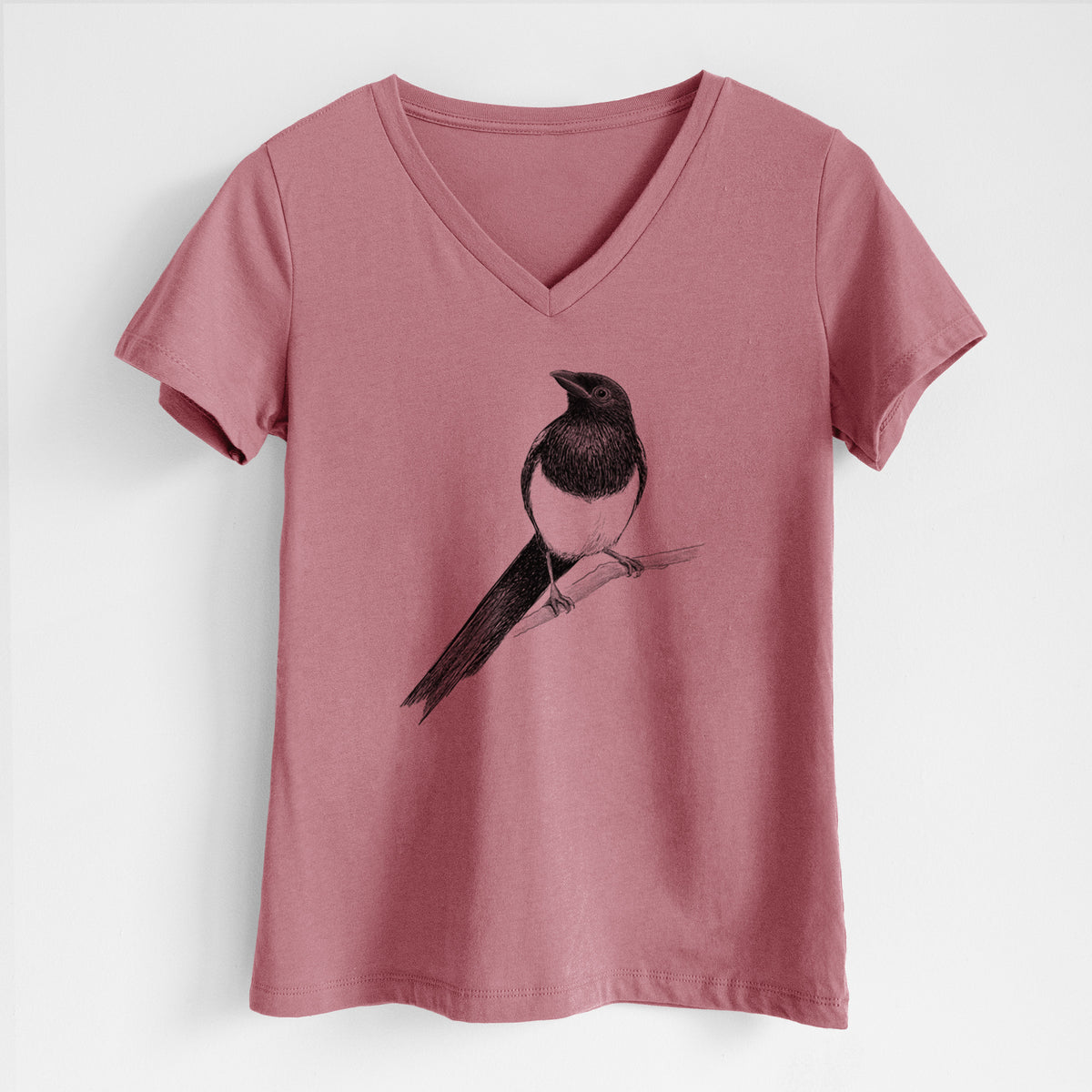 Mauve pink women's relaxed fit cotton V-neck t-shirt laid flat, printed with a detailed black ink sketch of a black-billed magpie perched on a branch with its long tail.
