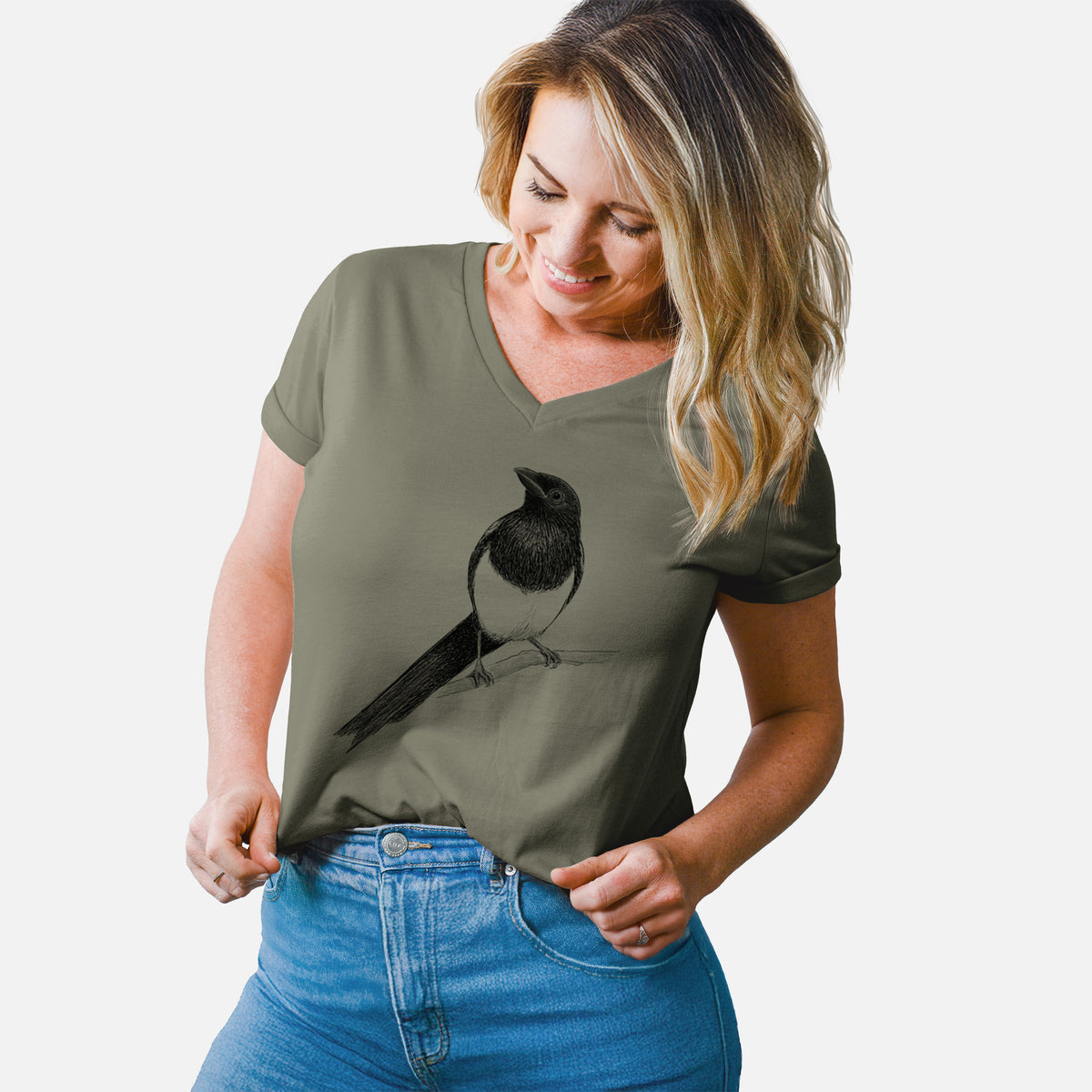 Woman wearing a military green women's relaxed fit cotton V-neck t-shirt printed with a detailed black ink sketch of a black-billed magpie perched on a branch with its long tail.