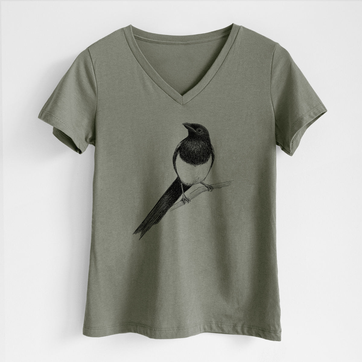 Military green women's relaxed fit cotton V-neck t-shirt laid flat, printed with a detailed black ink sketch of a black-billed magpie perched on a branch with its long tail.