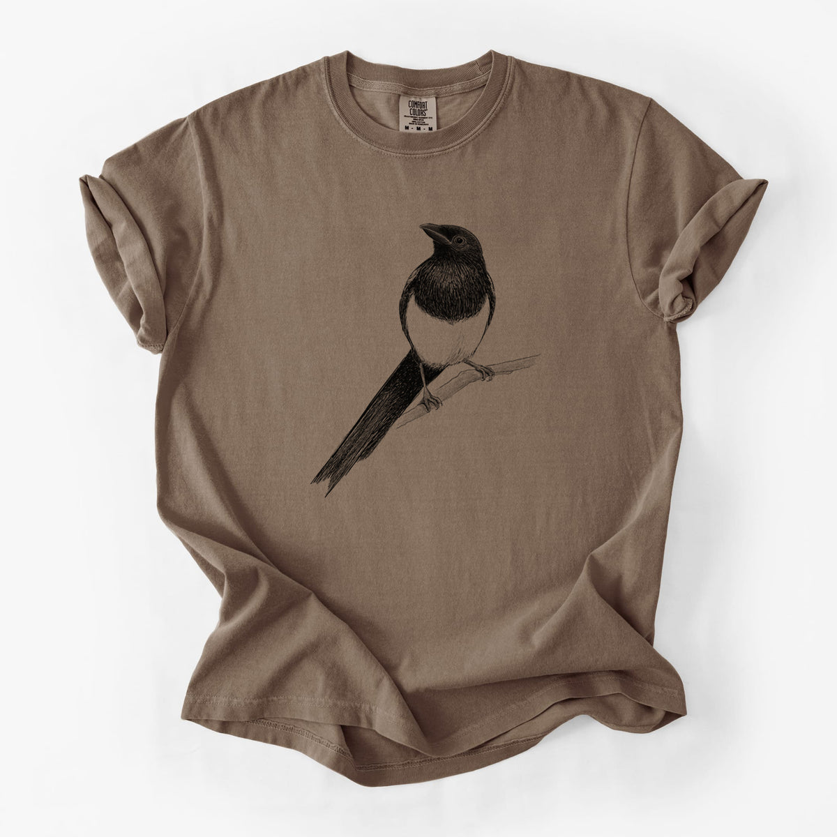 Espresso brown Comfort Colors t-shirt laid flat, printed with a detailed black ink sketch of a black-billed magpie perched on a branch with its long tail.