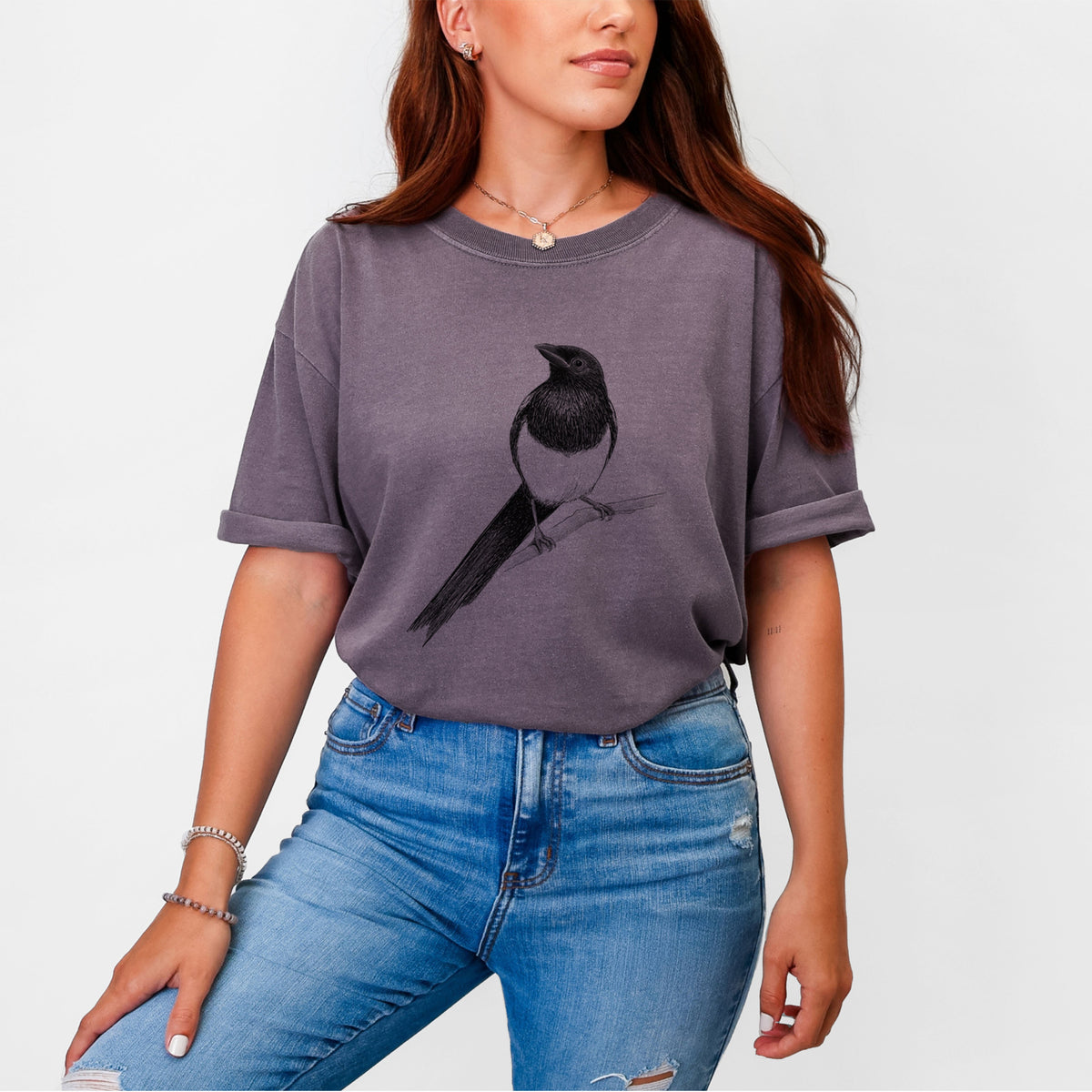 Woman wearing a Comfort Colors t-shirt printed with a detailed black ink sketch of a black-billed magpie perched on a branch with its long tail.