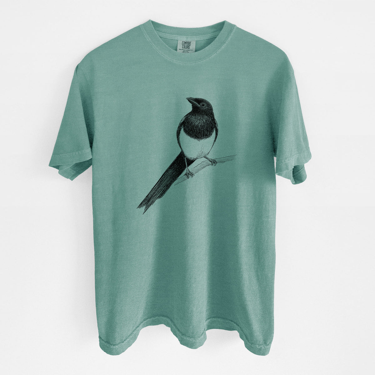 Reef green Comfort Colors t-shirt laid flat, printed with a detailed black ink sketch of a black-billed magpie perched on a branch with its long tail.