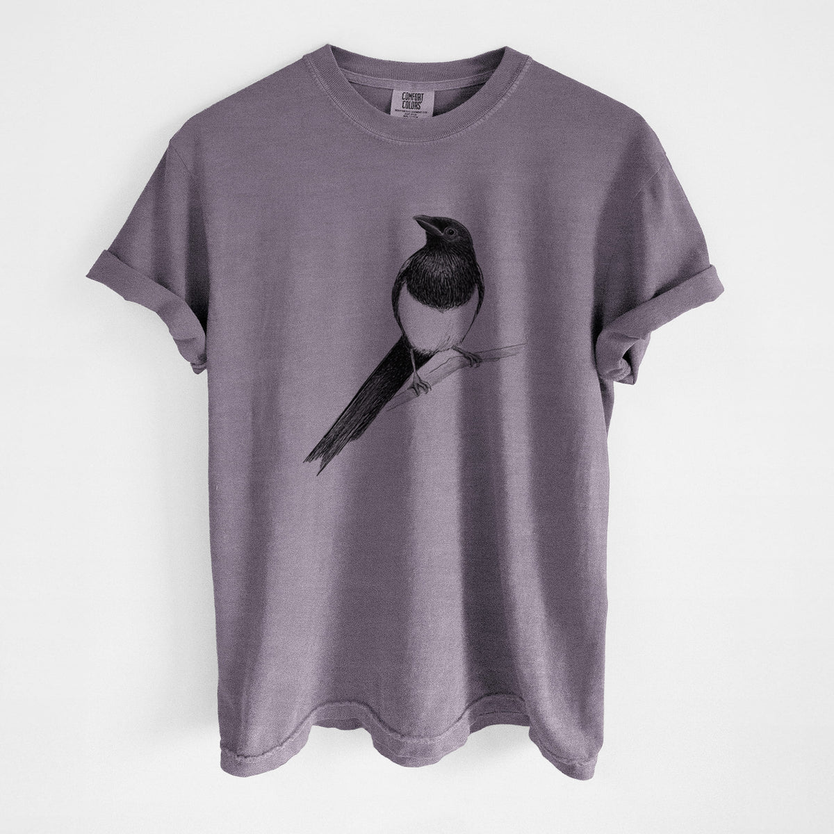 Wine red Comfort Colors t-shirt laid flat, printed with a detailed black ink sketch of a black-billed magpie perched on a branch with its long tail.