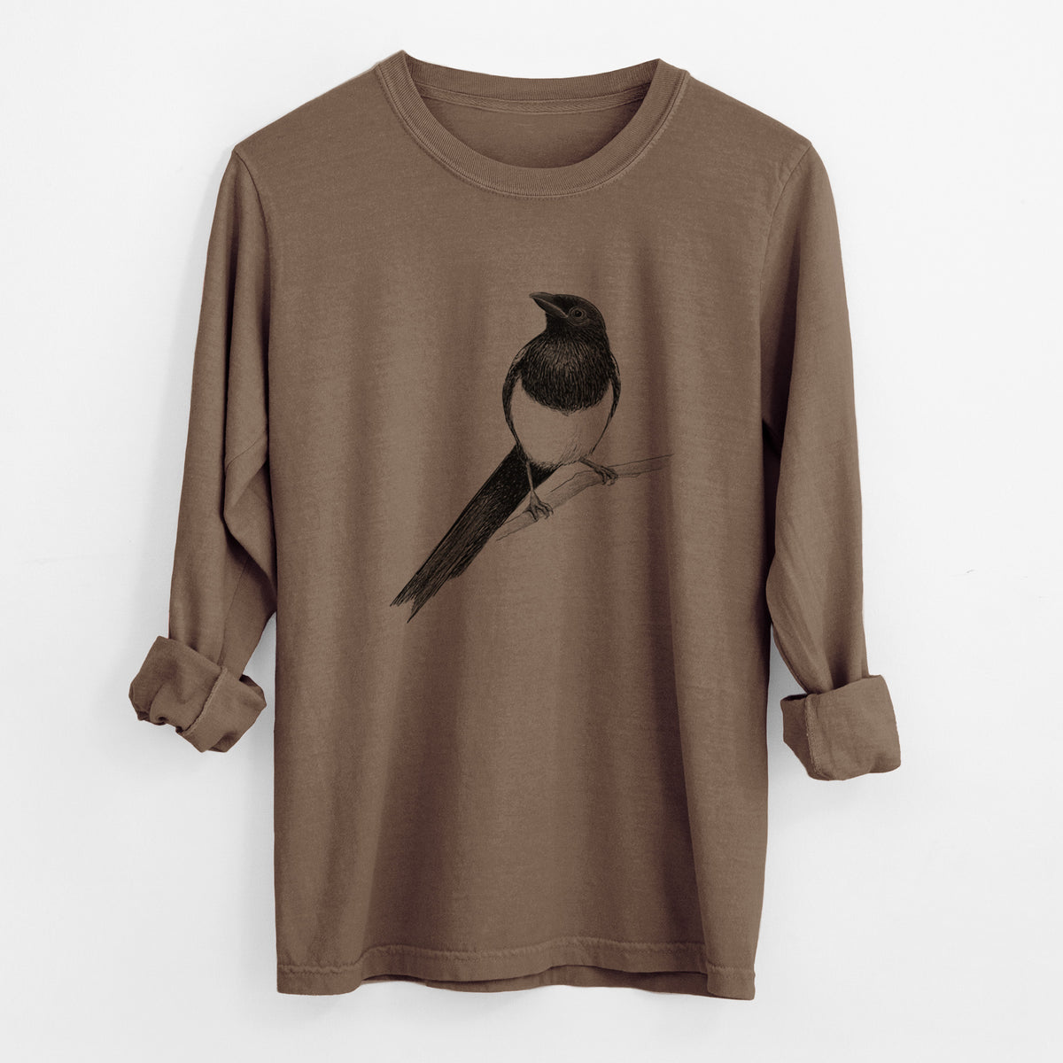 Espresso brown Comfort Colors long sleeve shirt laid flat with the cuffs rolled, printed with a detailed black ink sketch of a black-billed magpie perched on a branch with its long tail.
