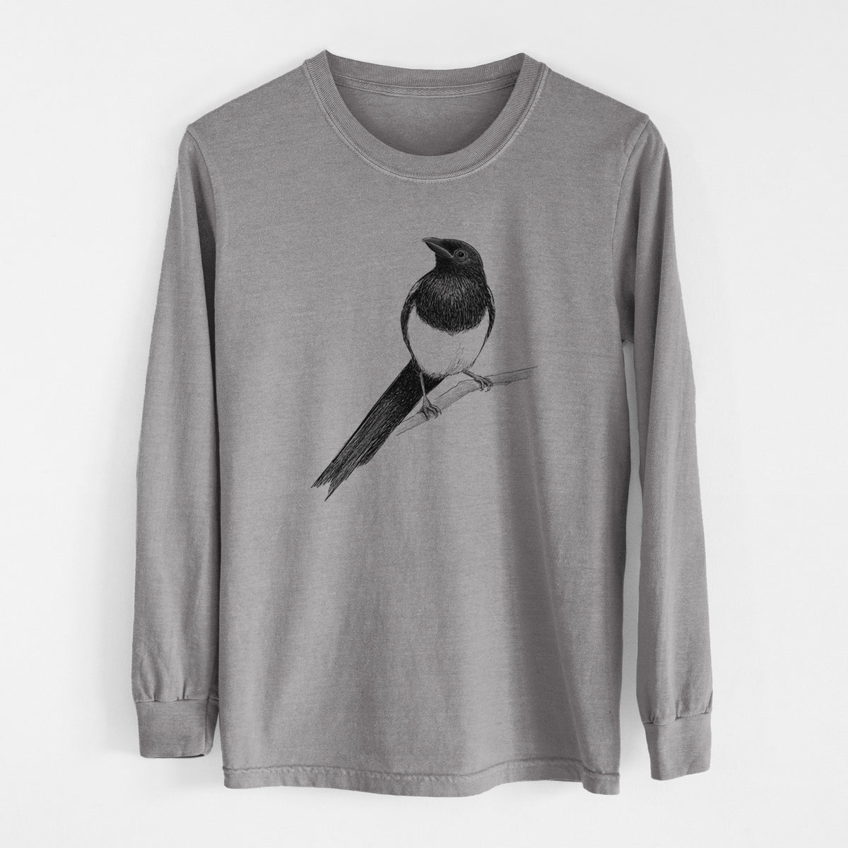 Grey Comfort Colors long sleeve shirt laid flat, printed with a detailed black ink sketch of a black-billed magpie perched on a branch with its long tail.