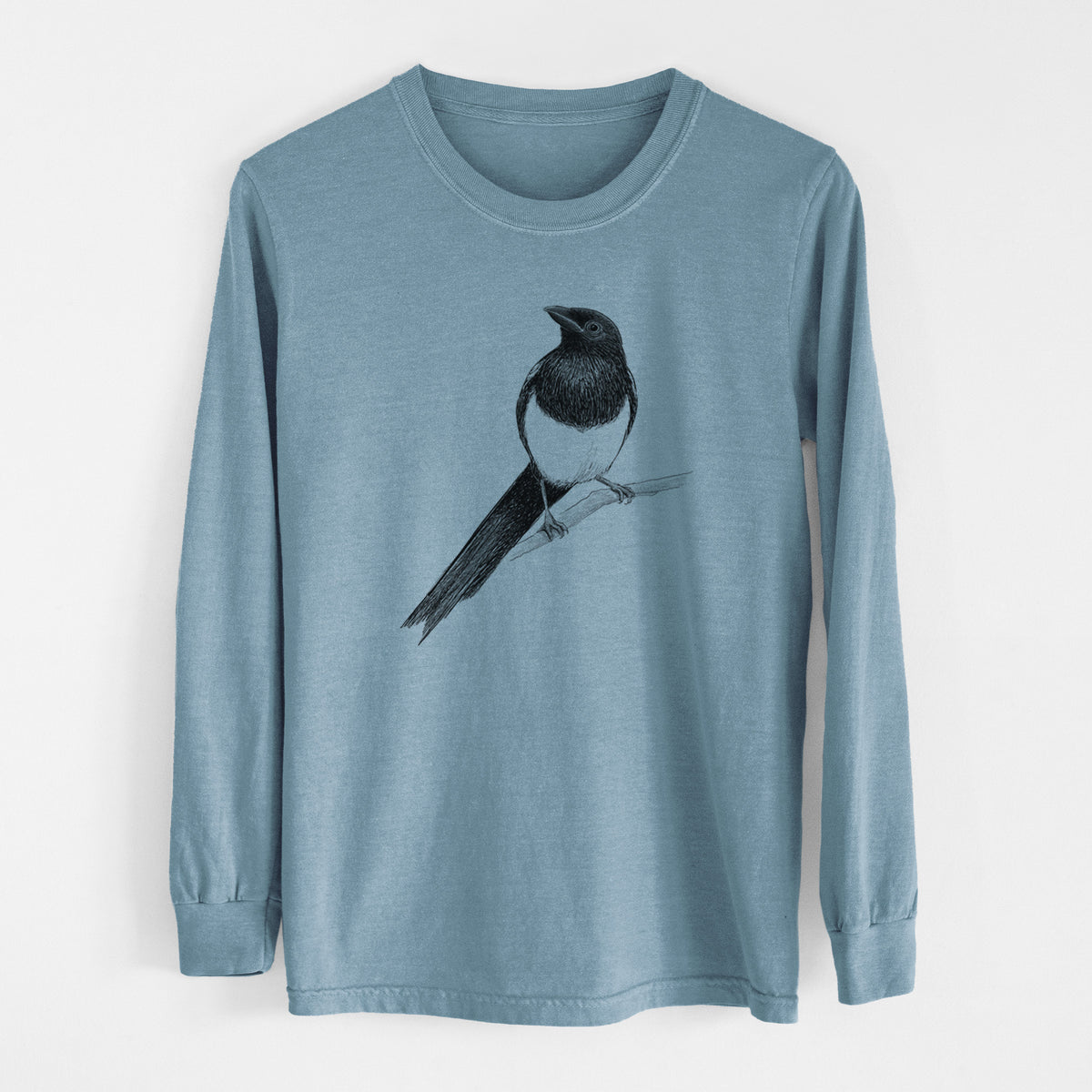Steel blue Comfort Colors long sleeve shirt laid flat, printed with a detailed black ink sketch of a black-billed magpie perched on a branch with its long tail.