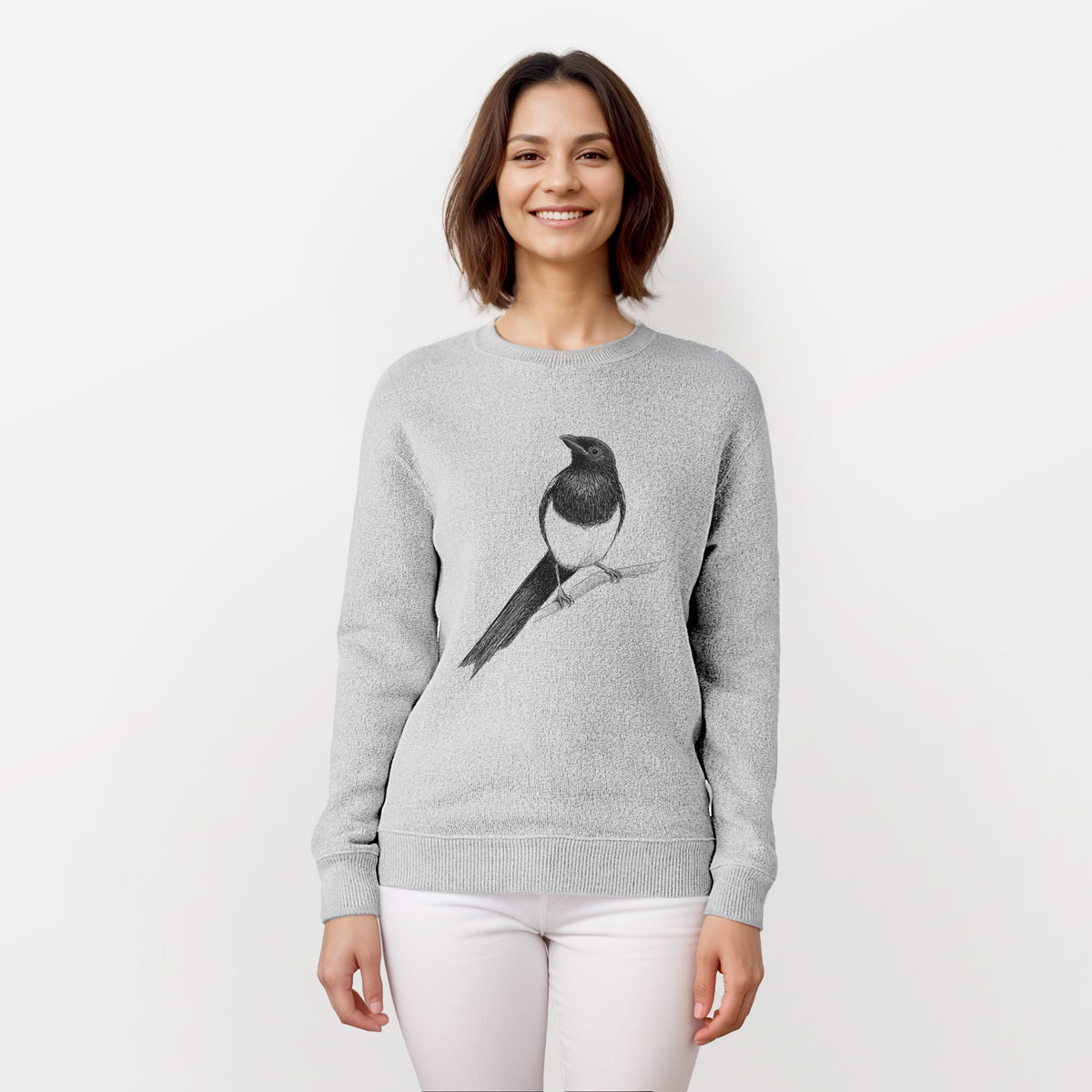 Woman wearing a knit sweatshirt printed with a detailed black ink sketch of a black-billed magpie perched on a branch with its long tail.