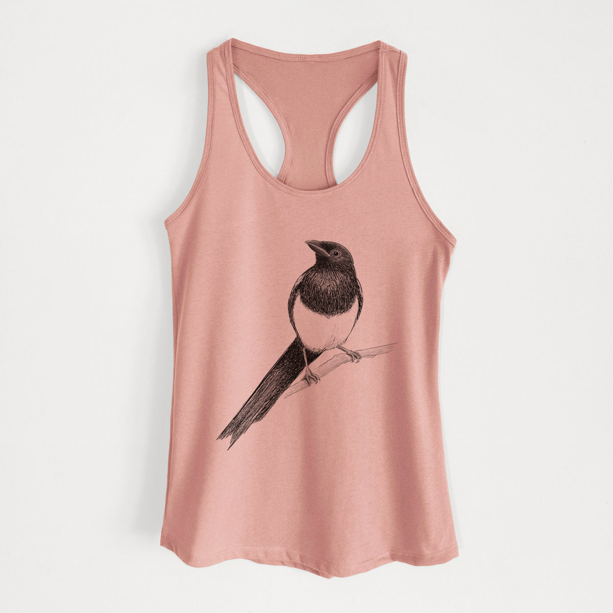 Desert pink women's racerback tank top laid flat, printed with a detailed black ink sketch of a black-billed magpie perched on a branch with its long tail.