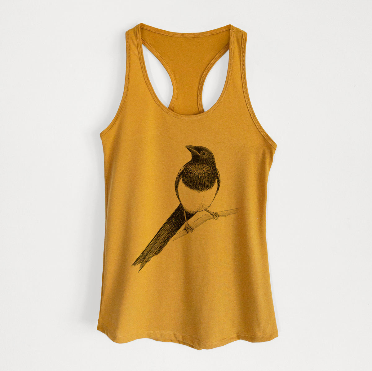 Gold women's racerback tank top laid flat, printed with a detailed black ink sketch of a black-billed magpie perched on a branch with its long tail.