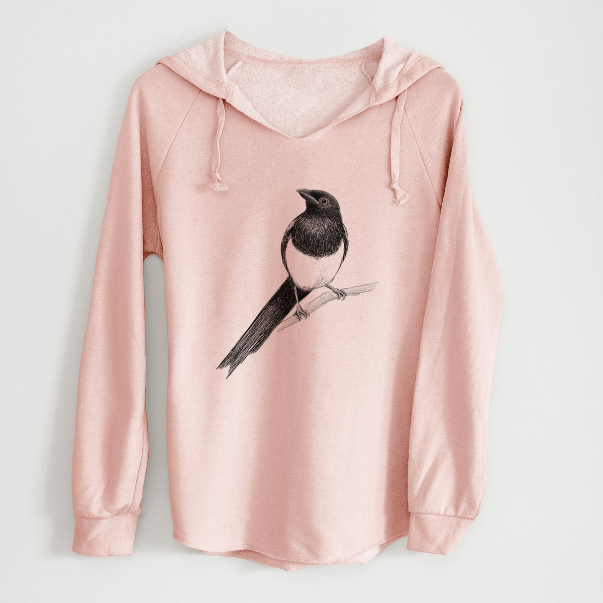 Blush pink women's Cali Wave hooded sweatshirt laid flat, printed with a detailed black ink sketch of a black-billed magpie perched on a branch with its long tail.