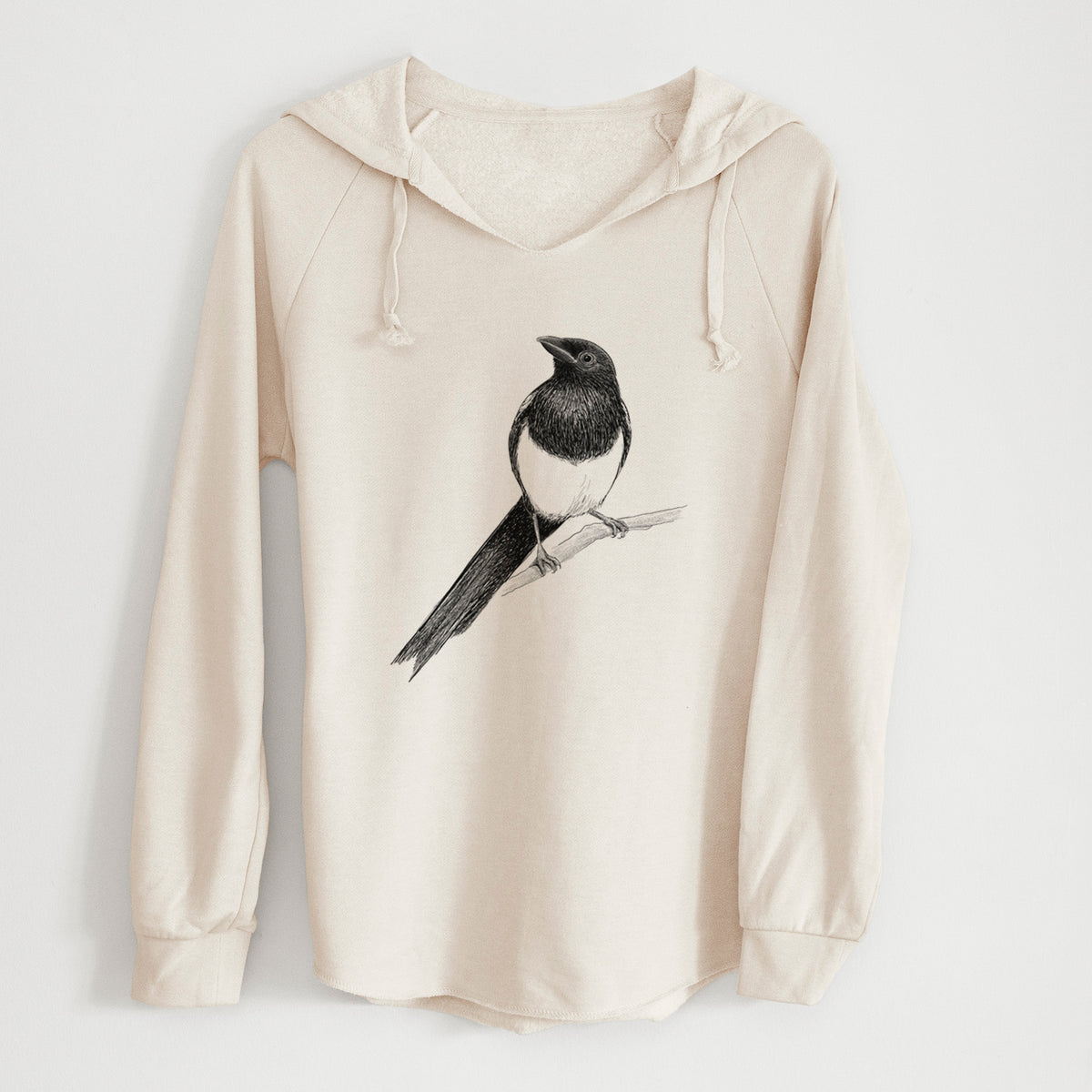 Bone cream women's Cali Wave hooded sweatshirt laid flat, printed with a detailed black ink sketch of a black-billed magpie perched on a branch with its long tail.