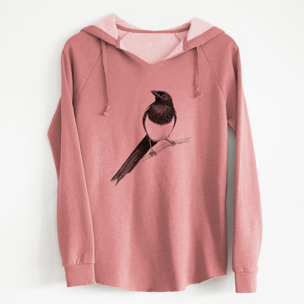 Dusty rose women's Cali Wave hooded sweatshirt laid flat, printed with a detailed black ink sketch of a black-billed magpie perched on a branch with its long tail.