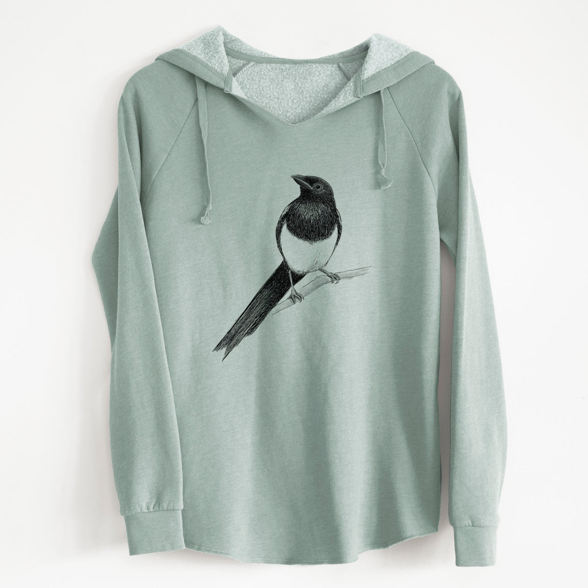 Sage green women's Cali Wave hooded sweatshirt laid flat, printed with a detailed black ink sketch of a black-billed magpie perched on a branch with its long tail.