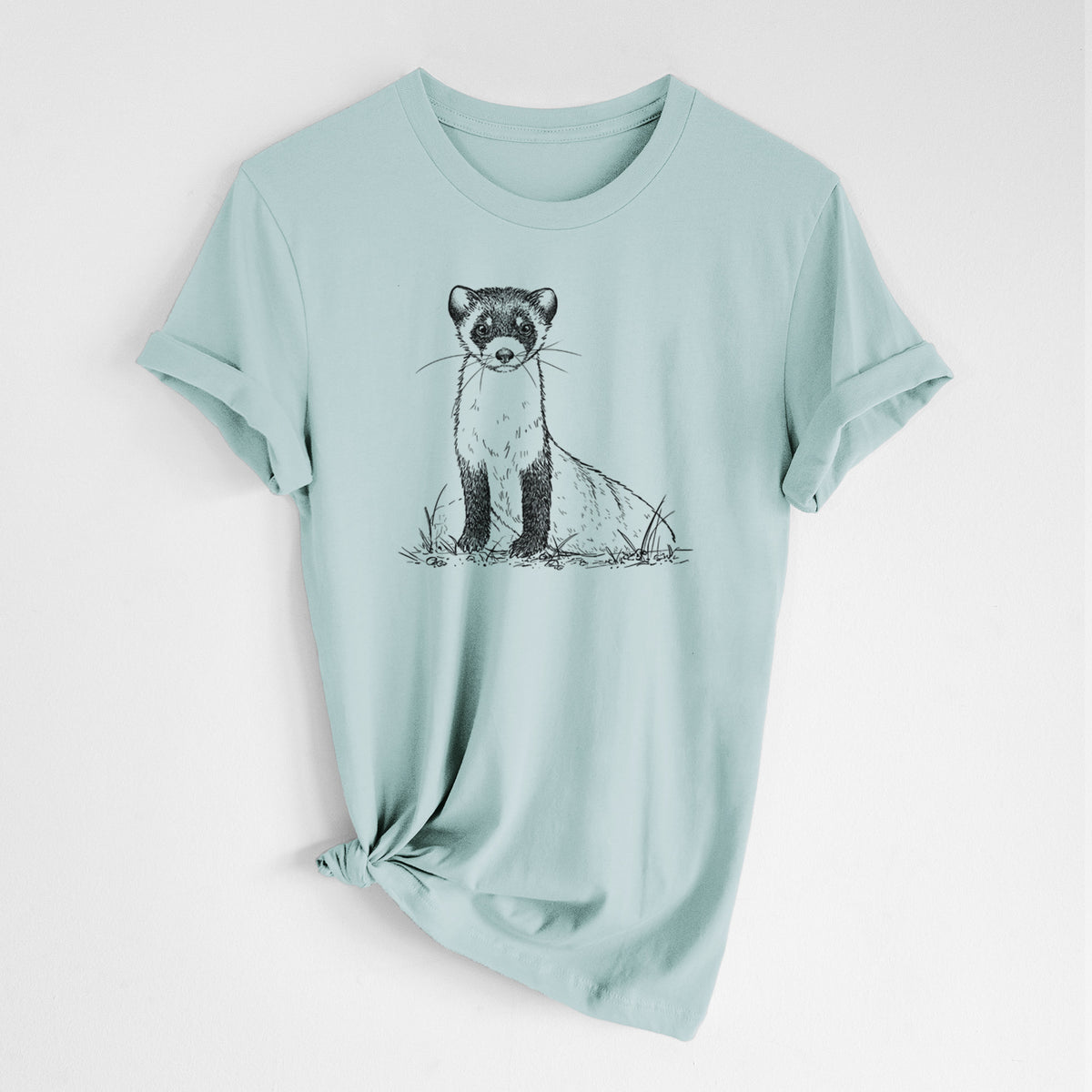 Dusty blue lightweight cotton t-shirt laid flat with the sleeves rolled, printed with a detailed black ink illustration of a black-footed ferret sitting on the ground.