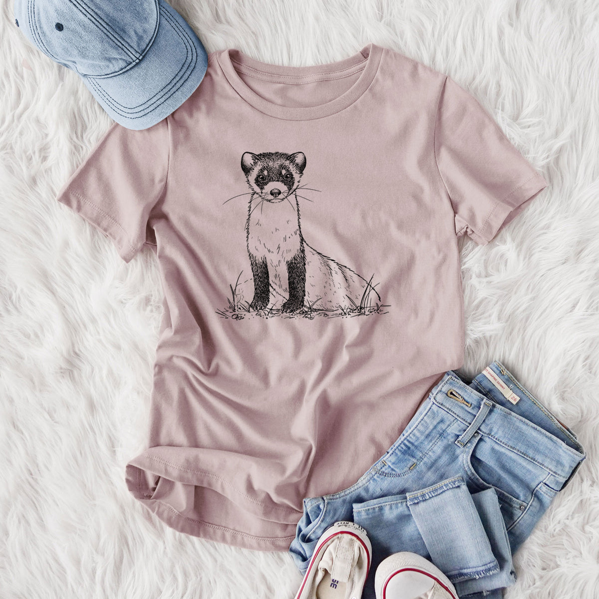 Women's relaxed fit cotton t-shirt printed with a detailed black ink illustration of a black-footed ferret sitting on the ground, styled flat on a white faux fur rug with jeans.