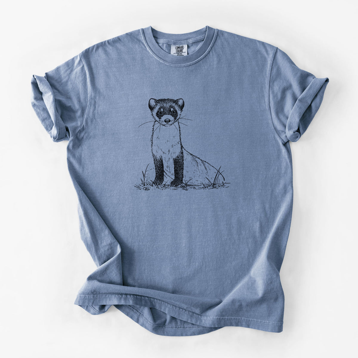 Blue jean Comfort Colors t-shirt laid flat, printed with a detailed black ink illustration of a black-footed ferret sitting on the ground.