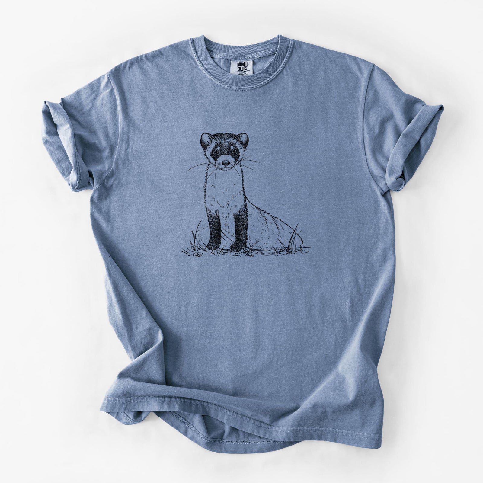 Blue jean Comfort Colors t-shirt laid flat, printed with a detailed black ink illustration of a black-footed ferret sitting on the ground.