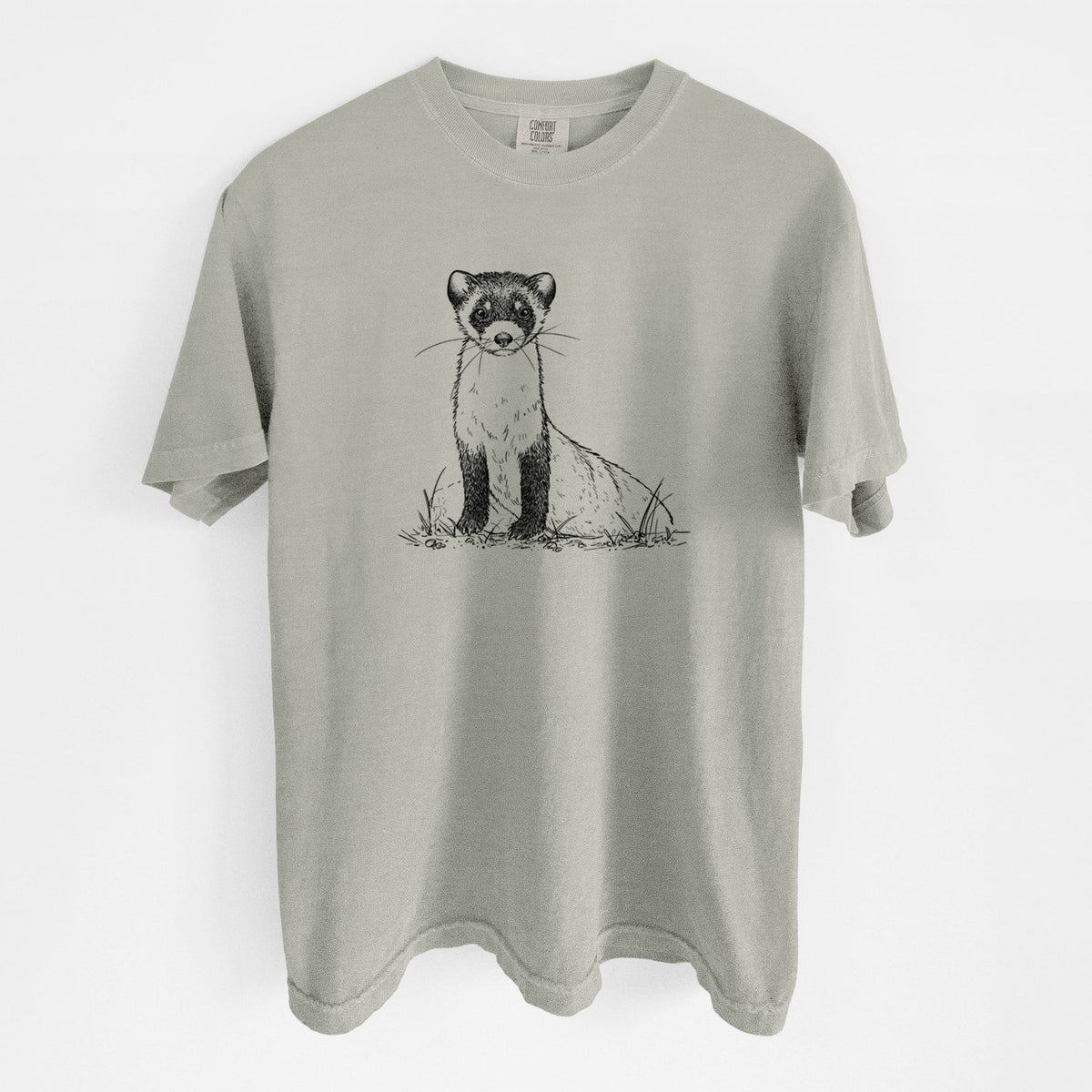 Sandstone beige Comfort Colors t-shirt laid flat, printed with a detailed black ink illustration of a black-footed ferret sitting on the ground.