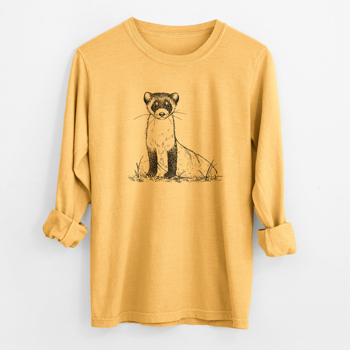 Golden wheat yellow Comfort Colors long sleeve shirt laid flat with the cuffs rolled, printed with a detailed black ink illustration of a black-footed ferret sitting on the ground.
